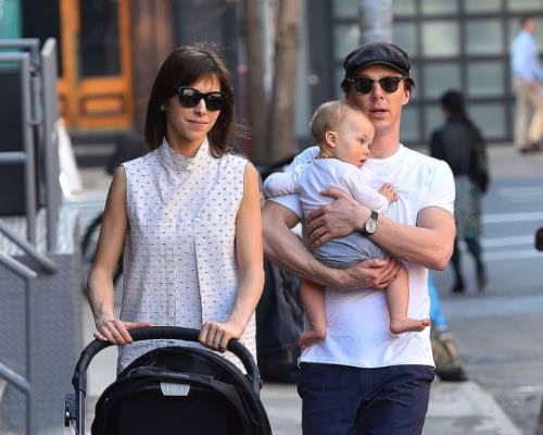 Hal Auden Cumberbatch in a white baby dress with his father in a white t-shirt and blue pants and his mother in a white tops with a luggage.